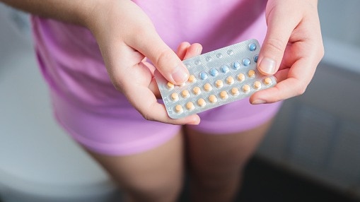 684814e04b85b-top-view-of-unidentified-young-woman-dressed-in-a-pink-pajama-holding-her-contracept.jpeg